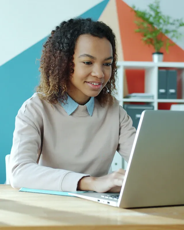 A smiling woman working on her laptop at a desk